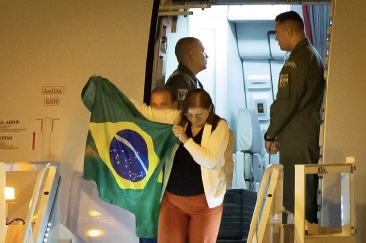 Primeiros repatriados a descerem de avião abrem bandeira do Brasil